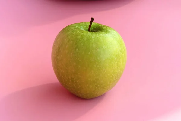 Manzana verde sobre fondo rosa. Jugosa fruta madura hermosa — Foto de Stock