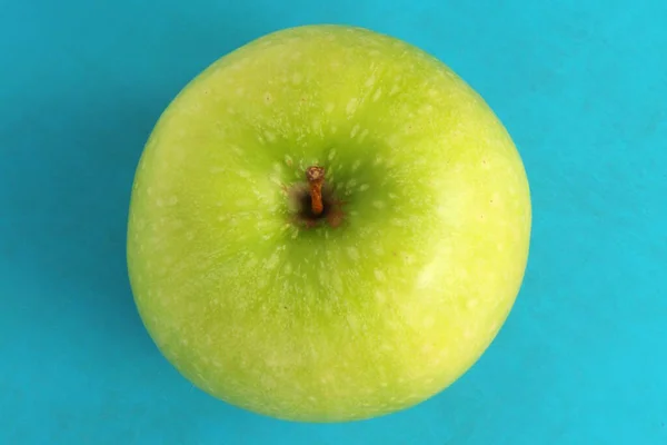 Zielone jabłko na niebieskim tle. Soczyste dojrzałe piękne owoce — Zdjęcie stockowe