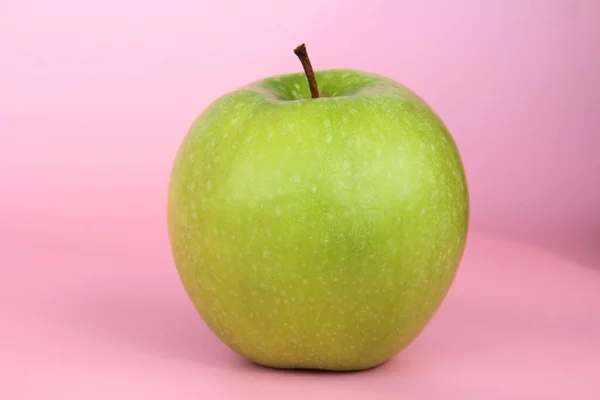 Manzana verde sobre fondo rosa. Jugosa fruta madura hermosa — Foto de Stock