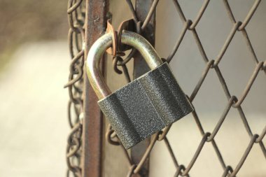 Gri demir, parlak asma kilit sokağın demir kapısında asılı.