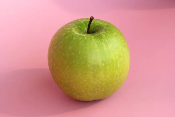 Maçã verde em um fundo rosa. Fruta bonita madura suculenta — Fotografia de Stock