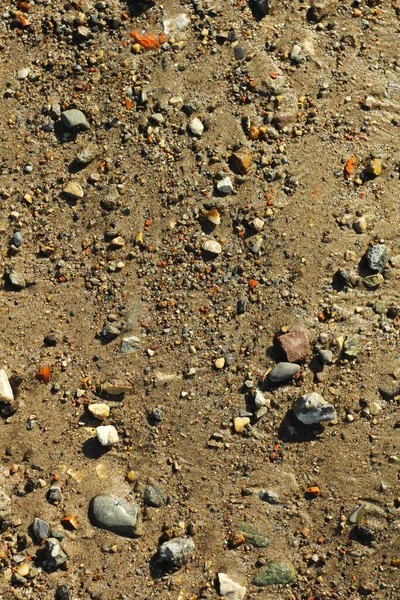 Pequeñas piedras y arena. La textura natural del suelo. Orilla de un embalse con una playa y guijarros —  Fotos de Stock