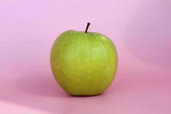 Maçã verde em um fundo rosa. Fruta bonita madura suculenta — Fotografia de Stock