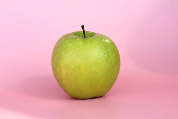Maçã verde em um fundo rosa. Fruta bonita madura suculenta — Fotografia de Stock