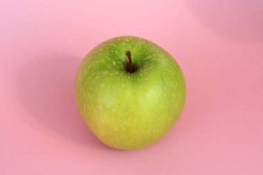 Pembe arka planda yeşil elma. Sulu, olgun, güzel meyve