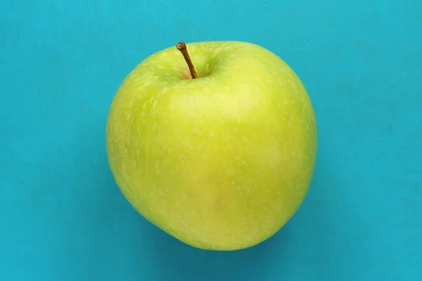 Maçã verde sobre um fundo azul. Fruta bonita madura suculenta — Fotografia de Stock