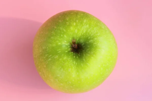 Zielone jabłko na różowym tle. Soczyste dojrzałe piękne owoce — Zdjęcie stockowe