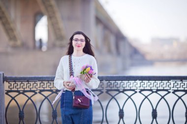 Güzel bir kız elinde bir buket bahar çiçeğiyle gezinti güvertesinde yürüyor, bir buket sümbül.