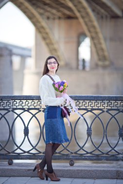 Güzel bir kız elinde bir buket bahar çiçeğiyle gezinti güvertesinde yürüyor, bir buket sümbül.