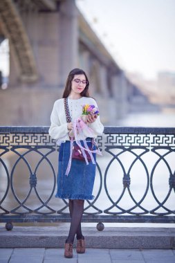 Güzel bir kız elinde bir buket bahar çiçeğiyle gezinti güvertesinde yürüyor, bir buket sümbül.