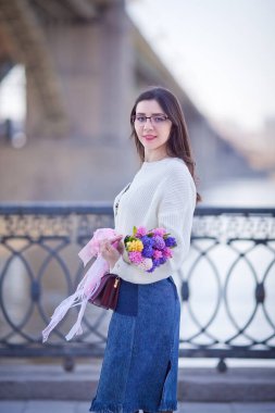 Güzel bir kız elinde bir buket bahar çiçeğiyle gezinti güvertesinde yürüyor, bir buket sümbül.