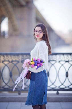 Güzel bir kız elinde bir buket bahar çiçeğiyle gezinti güvertesinde yürüyor, bir buket sümbül.