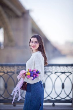 Güzel bir kız elinde bir buket bahar çiçeğiyle gezinti güvertesinde yürüyor, bir buket sümbül.