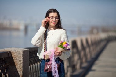 Güzel bir kız elinde bir buket bahar çiçeğiyle gezinti güvertesinde yürüyor, bir buket sümbül.