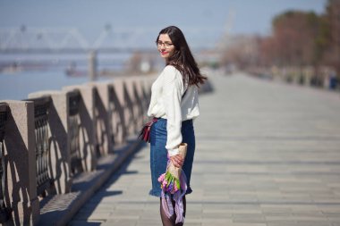 Güzel bir kız elinde bir buket bahar çiçeğiyle gezinti güvertesinde yürüyor, bir buket sümbül.