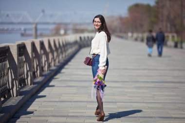 Güzel bir kız elinde bir buket bahar çiçeğiyle gezinti güvertesinde yürüyor, bir buket sümbül.