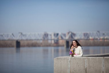 Güzel bir kız elinde bir buket bahar çiçeğiyle gezinti güvertesinde yürüyor, bir buket sümbül.