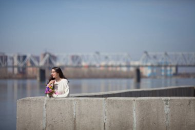 Güzel bir kız elinde bir buket bahar çiçeğiyle gezinti güvertesinde yürüyor, bir buket sümbül.