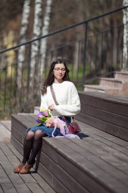 Güzel bir kız elinde bir buket bahar çiçeğiyle gezinti güvertesinde yürüyor, bir buket sümbül.