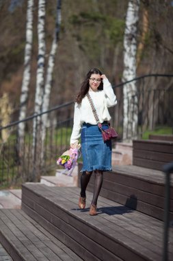 Güzel bir kız elinde bir buket bahar çiçeğiyle gezinti güvertesinde yürüyor, bir buket sümbül.