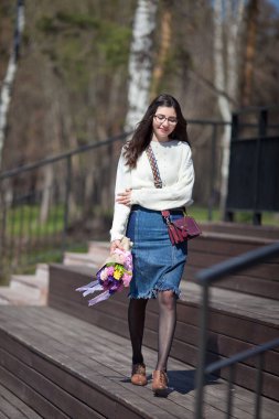 Güzel bir kız elinde bir buket bahar çiçeğiyle gezinti güvertesinde yürüyor, bir buket sümbül.
