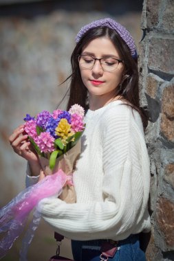 Güzel bir kız elinde bir buket bahar çiçeğiyle gezinti güvertesinde yürüyor, bir buket sümbül.