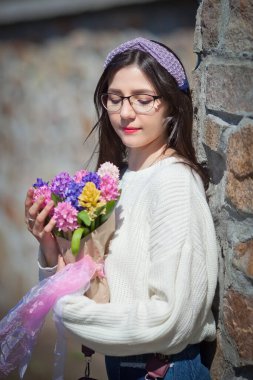 Güzel bir kız elinde bir buket bahar çiçeğiyle gezinti güvertesinde yürüyor, bir buket sümbül.