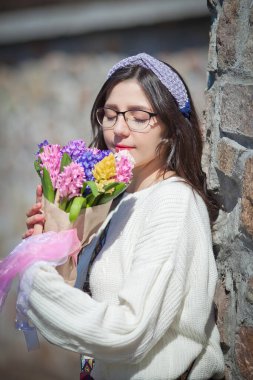 Güzel bir kız elinde bir buket bahar çiçeğiyle gezinti güvertesinde yürüyor, bir buket sümbül.