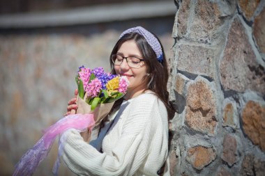 Güzel bir kız elinde bir buket bahar çiçeğiyle gezinti güvertesinde yürüyor, bir buket sümbül.