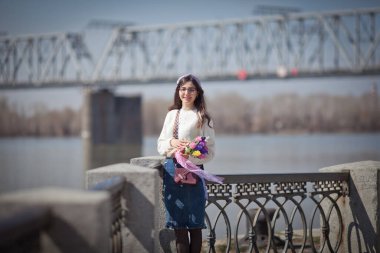 Güzel bir kız elinde bir buket bahar çiçeğiyle gezinti güvertesinde yürüyor, bir buket sümbül.