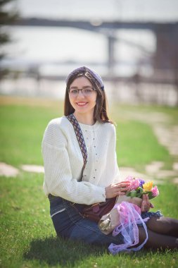 Güzel bir kız elinde bir buket bahar çiçeğiyle gezinti güvertesinde yürüyor, bir buket sümbül.