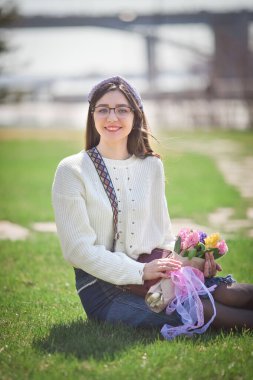 Güzel bir kız elinde bir buket bahar çiçeğiyle gezinti güvertesinde yürüyor, bir buket sümbül.