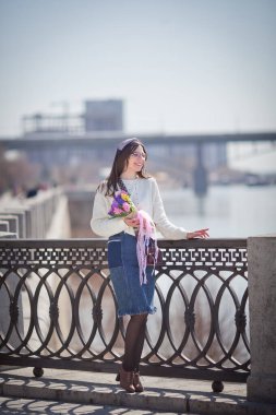 Güzel bir kız elinde bir buket bahar çiçeğiyle gezinti güvertesinde yürüyor, bir buket sümbül.