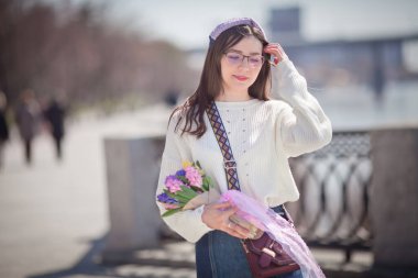 Güzel bir kız elinde bir buket bahar çiçeğiyle gezinti güvertesinde yürüyor, bir buket sümbül.