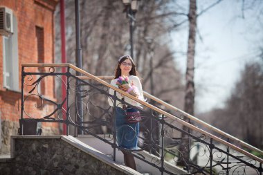 Güzel bir kız elinde bir buket bahar çiçeğiyle gezinti güvertesinde yürüyor, bir buket sümbül.