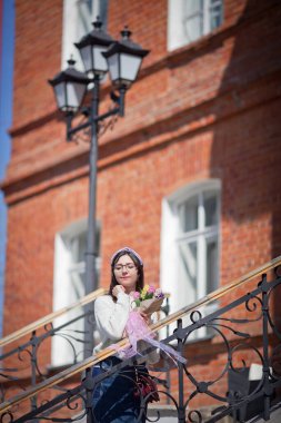 Güzel bir kız elinde bir buket bahar çiçeğiyle gezinti güvertesinde yürüyor, bir buket sümbül.