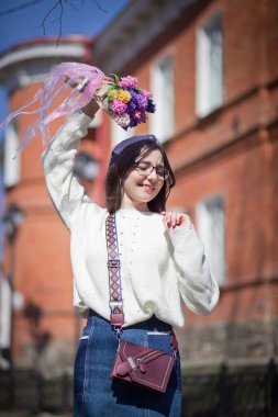 Güzel bir kız elinde bir buket bahar çiçeğiyle gezinti güvertesinde yürüyor, bir buket sümbül.