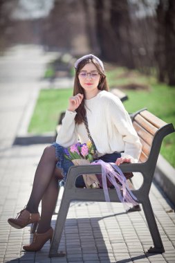 Güzel bir kız elinde bir buket bahar çiçeğiyle gezinti güvertesinde yürüyor, bir buket sümbül.