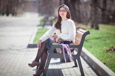 Güzel bir kız elinde bir buket bahar çiçeğiyle gezinti güvertesinde yürüyor, bir buket sümbül.