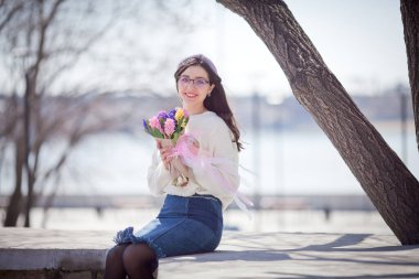 Güzel bir kız elinde bir buket bahar çiçeğiyle gezinti güvertesinde yürüyor, bir buket sümbül.