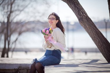 Güzel bir kız elinde bir buket bahar çiçeğiyle gezinti güvertesinde yürüyor, bir buket sümbül.