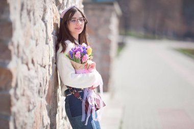 Güzel bir kız elinde bir buket bahar çiçeğiyle gezinti güvertesinde yürüyor, bir buket sümbül.