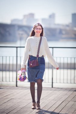 Güzel bir kız elinde bir buket bahar çiçeğiyle gezinti güvertesinde yürüyor, bir buket sümbül.