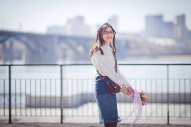 Güzel bir kız elinde bir buket bahar çiçeğiyle gezinti güvertesinde yürüyor, bir buket sümbül.