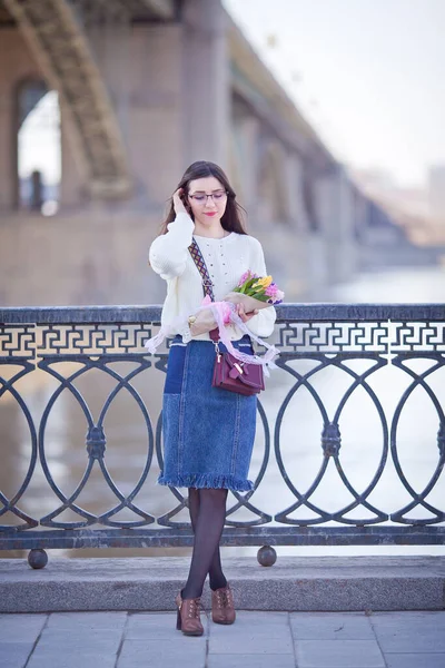 Güzel bir kız elinde bir buket bahar çiçeğiyle gezinti güvertesinde yürüyor, bir buket sümbül.