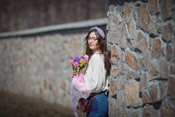 Güzel bir kız elinde bir buket bahar çiçeğiyle gezinti güvertesinde yürüyor, bir buket sümbül.