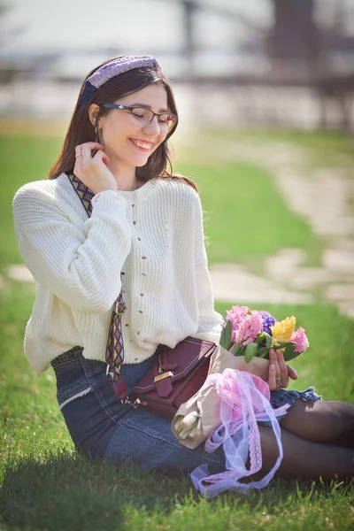 Güzel bir kız elinde bir buket bahar çiçeğiyle gezinti güvertesinde yürüyor, bir buket sümbül.