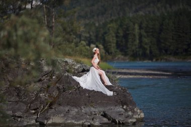 Deniz Kızının Hikayesi. Nymph Nehri 'nin Hikayesi. Beyaz elbiseli bir kız nehir kenarındaki kayalık bir sahilde duruyor. Altai 'de fotoğraf çekimi.