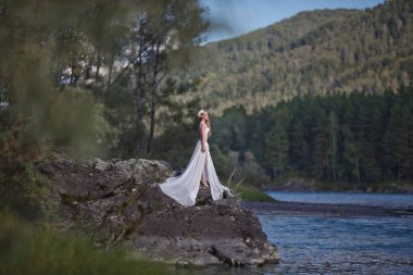 Deniz Kızının Hikayesi. Nymph Nehri 'nin Hikayesi. Beyaz elbiseli bir kız nehir kenarındaki kayalık bir sahilde duruyor. Altai 'de fotoğraf çekimi.