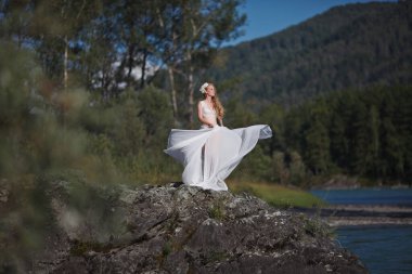 Deniz Kızının Hikayesi. Nymph Nehri 'nin Hikayesi. Beyaz elbiseli bir kız nehir kenarındaki kayalık bir sahilde duruyor. Altai 'de fotoğraf çekimi.